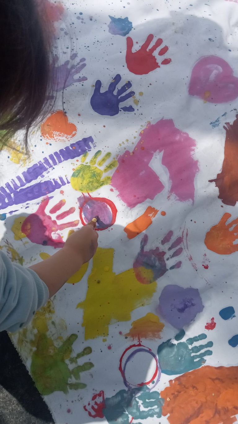 Manos infantiles pintando con témperas de colores sobre papel continuo
