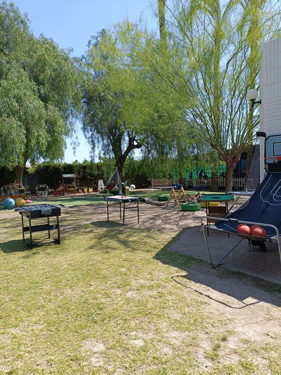 Zona recreativa del jardín con futbolín, mesa de air hockey, billar y canasta de baloncesto entre los árboles